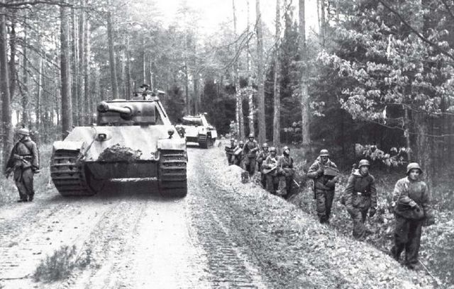 Infantería y paracaidistas avanzan junto a una columna de Panther Ausf G por una pista forestal en las Ardenas. Diciembre de 1944